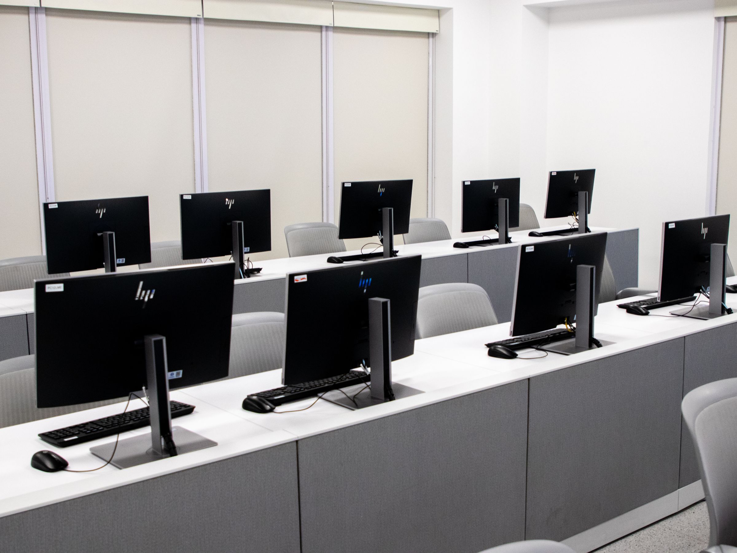 Rows of desktop computers with keyboards on long desks