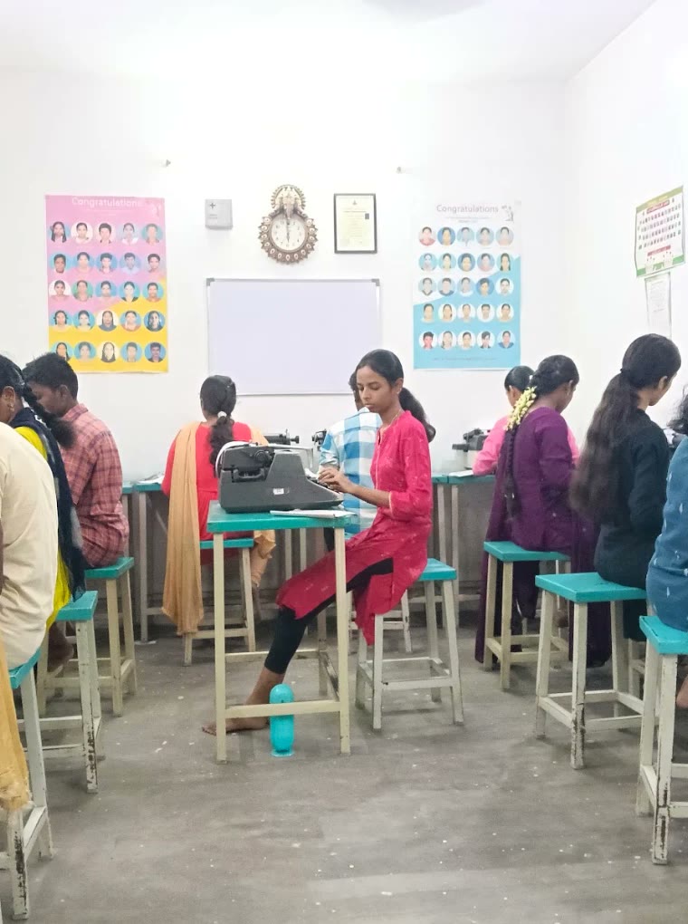Students at typewriters in a row, results posters on the wall behind them