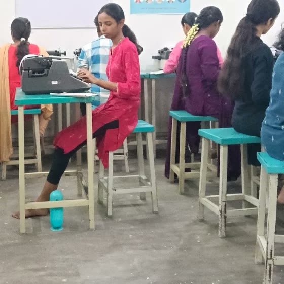 A student typing at her desk in the classroom