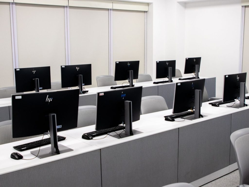 Rows of desktop computers with keyboards on long desks
