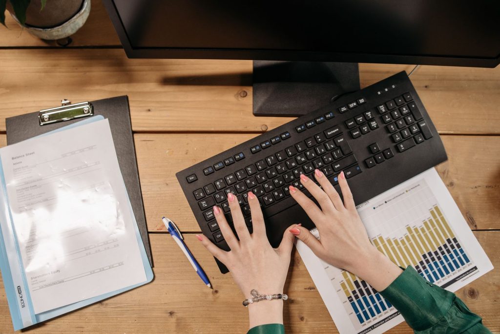 Hands typing on a black computer keyboard